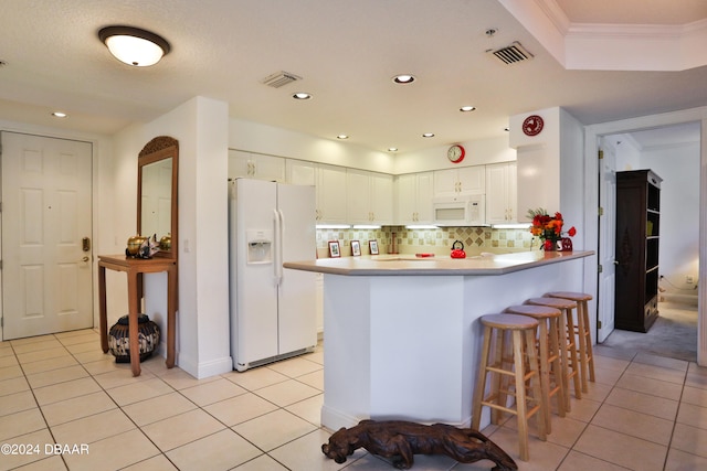 kitchen featuring white cabinetry, kitchen peninsula, light tile patterned floors, backsplash, and white appliances