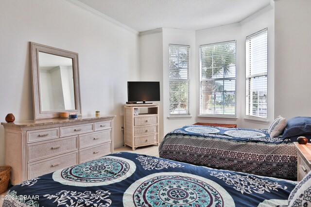 bedroom with multiple windows, a textured ceiling, and ornamental molding