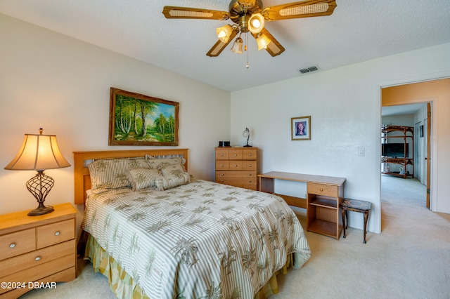 carpeted bedroom with ceiling fan and a textured ceiling