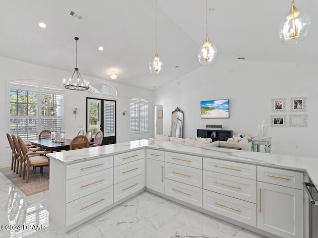 kitchen featuring white cabinets, an inviting chandelier, pendant lighting, and vaulted ceiling