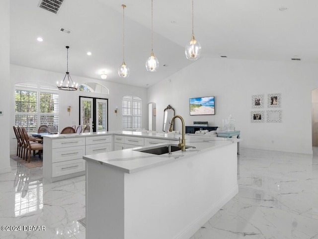 kitchen featuring white cabinets, sink, decorative light fixtures, and high vaulted ceiling