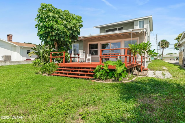 back of property featuring a wooden deck and a yard