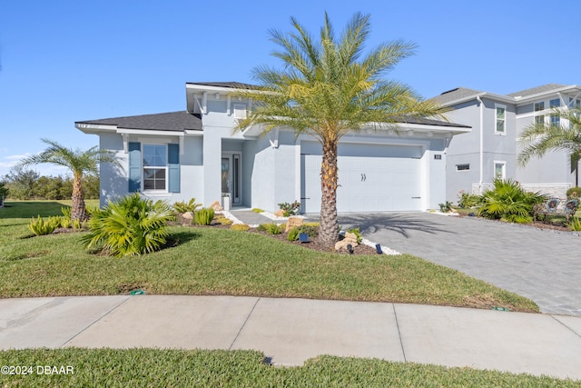 view of front of home featuring driveway, an attached garage, a front lawn, and stucco siding