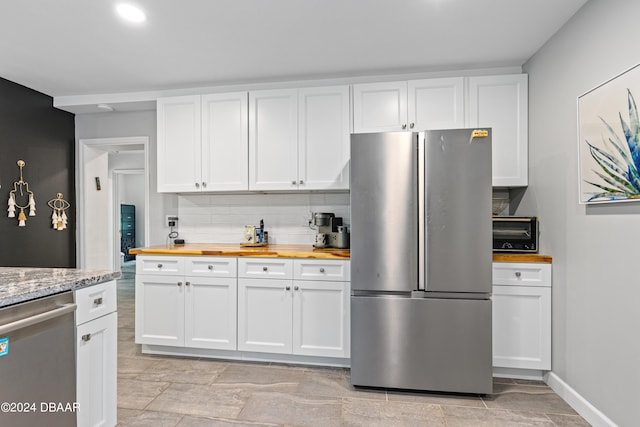 kitchen with white cabinetry, stainless steel appliances, and butcher block countertops