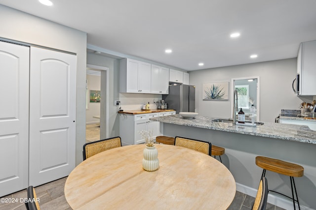 kitchen featuring stainless steel appliances, light hardwood / wood-style floors, light stone counters, sink, and white cabinetry