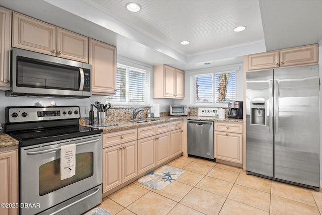 kitchen with sink, a raised ceiling, light tile patterned flooring, a healthy amount of sunlight, and appliances with stainless steel finishes