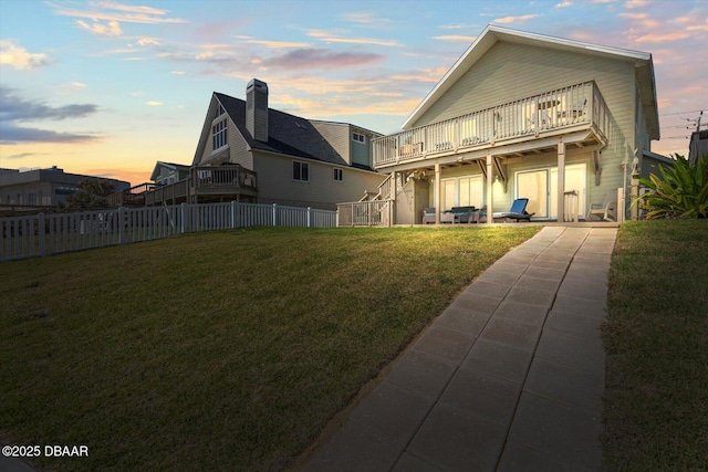 back house at dusk with a yard and a balcony