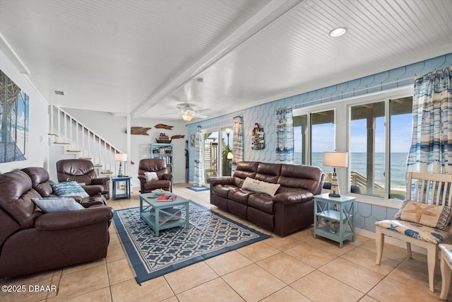 tiled living room featuring ceiling fan and a water view