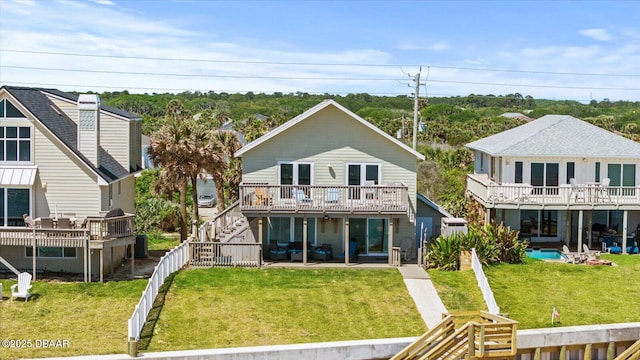 back of property featuring a lawn, a deck, and a patio area