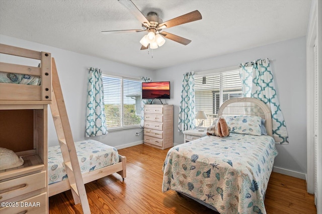 bedroom with ceiling fan, a textured ceiling, and hardwood / wood-style flooring