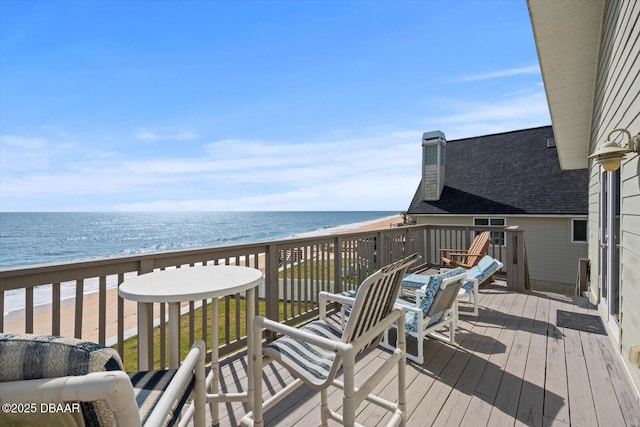 wooden deck featuring a beach view and a water view