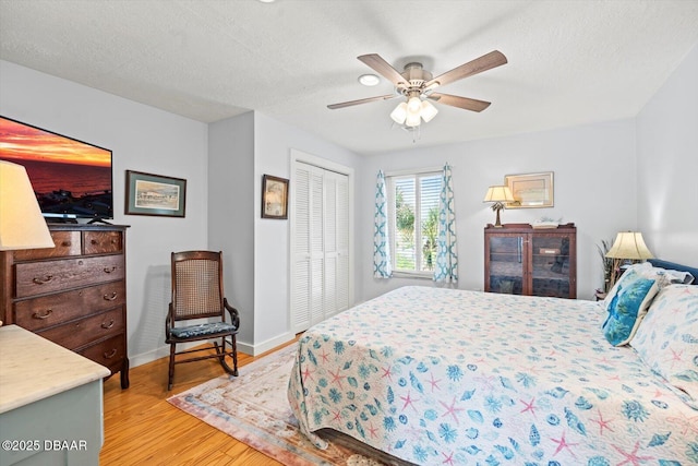 bedroom featuring ceiling fan, light hardwood / wood-style floors, a closet, and a textured ceiling