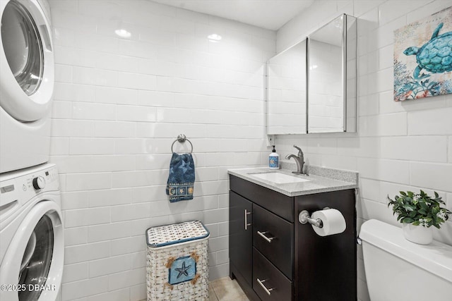 bathroom with toilet, stacked washer / dryer, and vanity