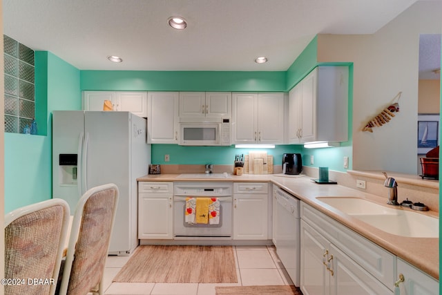 kitchen featuring white cabinetry, white appliances, sink, and light tile patterned floors