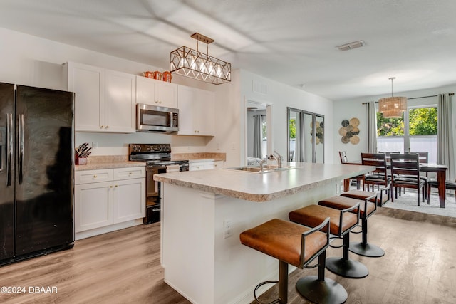 kitchen featuring visible vents, light countertops, light wood-style flooring, and black appliances