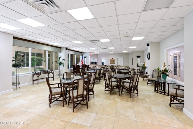 tiled dining area with a paneled ceiling