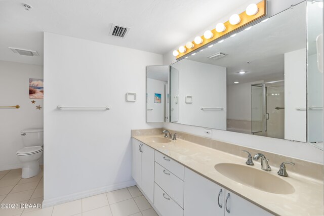 bathroom featuring vanity, a shower with door, tile patterned floors, and toilet