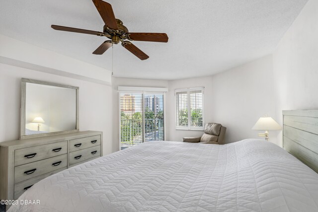 bedroom with ceiling fan, access to exterior, and a textured ceiling