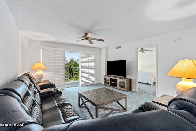 living room featuring ceiling fan, light colored carpet, and a textured ceiling