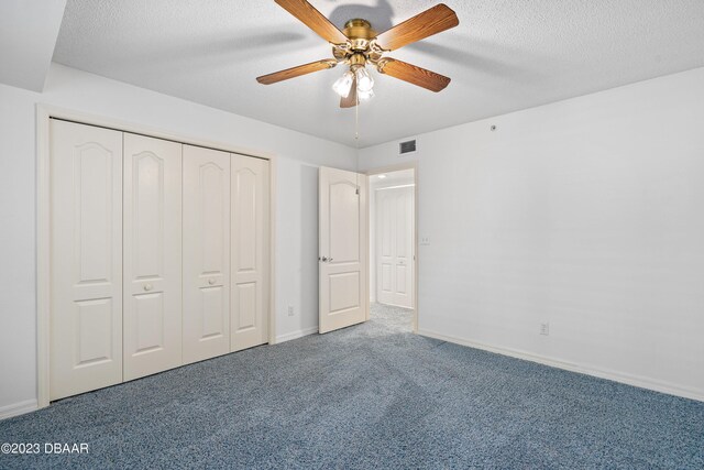 unfurnished bedroom with ceiling fan, a textured ceiling, carpet flooring, and a closet