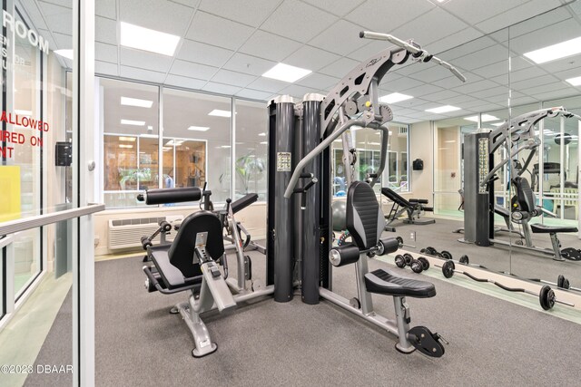 exercise room with a drop ceiling and a wall mounted AC