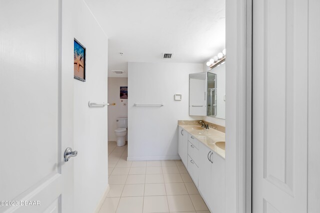 bathroom with toilet, vanity, and tile patterned flooring