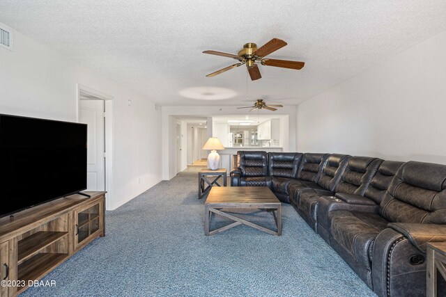 living room with ceiling fan, a textured ceiling, and carpet flooring