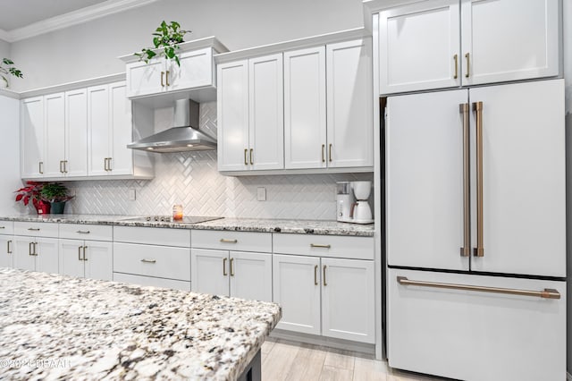 kitchen featuring white cabinetry, high end fridge, and wall chimney range hood