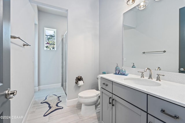 bathroom featuring vanity, hardwood / wood-style flooring, toilet, and a shower with door