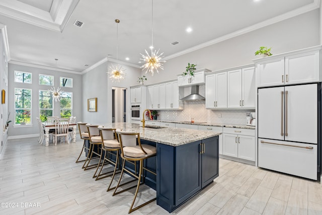 kitchen with high end white refrigerator, an island with sink, white cabinets, and exhaust hood