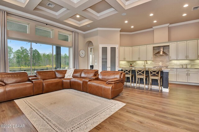 living area with visible vents, arched walkways, a high ceiling, and light wood-style flooring