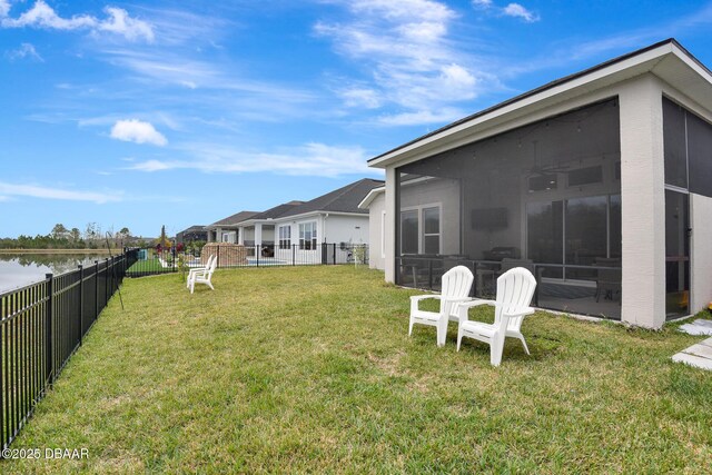 view of yard featuring a water view, a fenced backyard, and a sunroom