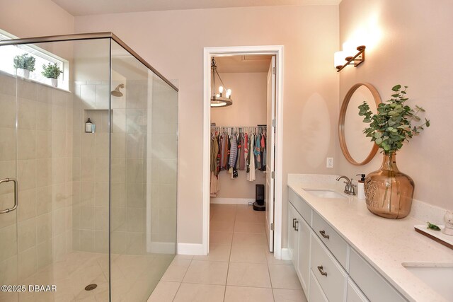 full bathroom with tile patterned floors, a stall shower, a sink, double vanity, and baseboards