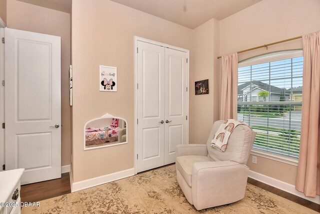 sitting room with baseboards, plenty of natural light, and wood finished floors