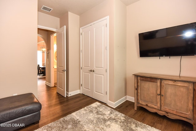 living area with arched walkways, visible vents, dark wood-type flooring, and baseboards