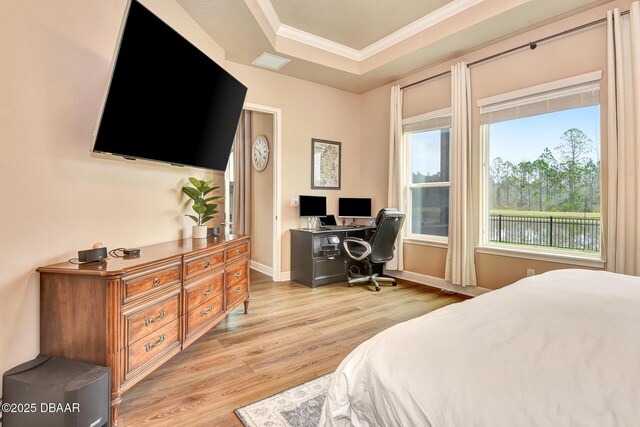 bedroom with visible vents, crown molding, baseboards, light wood-style floors, and a raised ceiling