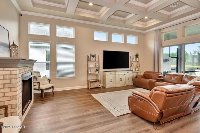 living area featuring beam ceiling, ornamental molding, a high ceiling, a fireplace, and light wood finished floors