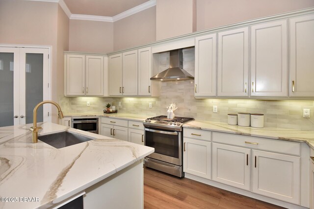 kitchen featuring white cabinetry, stainless steel appliances, wall chimney exhaust hood, and a sink