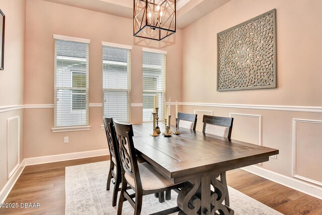 dining room featuring a notable chandelier, wood finished floors, and baseboards