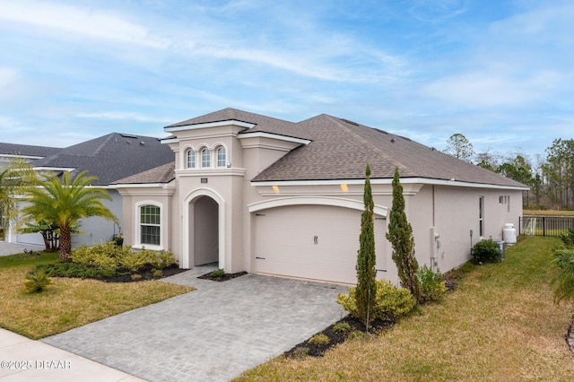 view of front of home featuring a garage, stucco siding, decorative driveway, and a front lawn