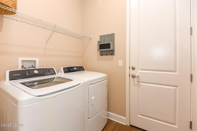 laundry room featuring baseboards, wood finished floors, laundry area, and washing machine and clothes dryer