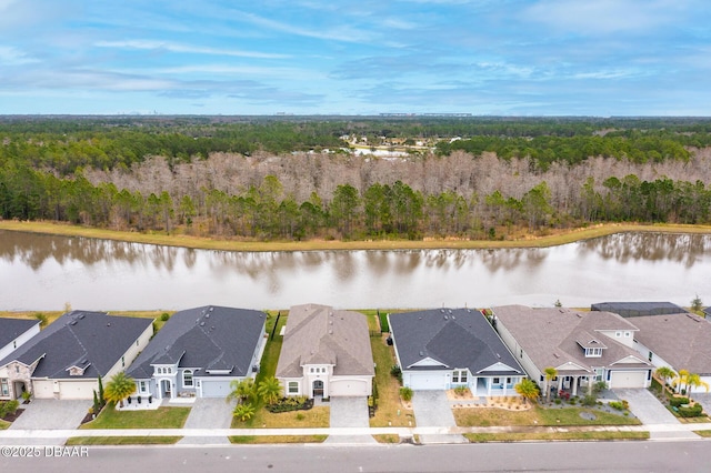 birds eye view of property featuring a forest view, a water view, and a residential view