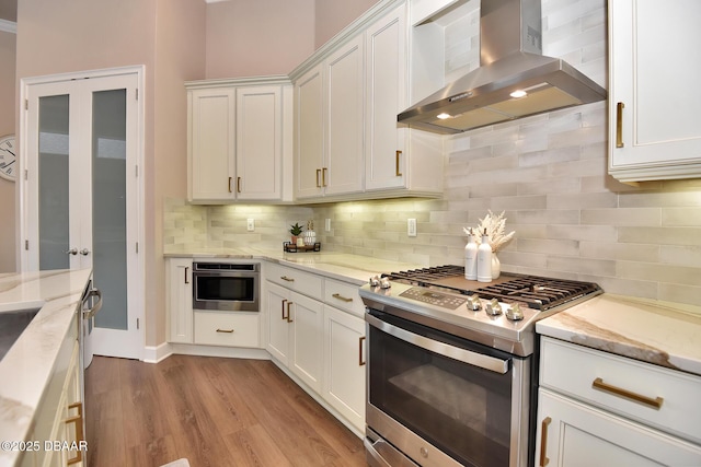 kitchen featuring white cabinetry, stainless steel appliances, and wall chimney exhaust hood