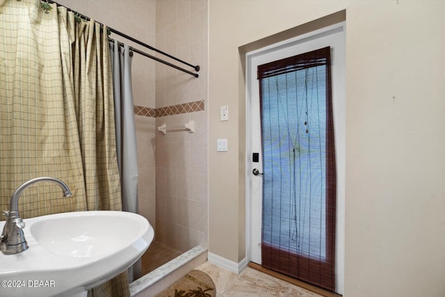 bathroom with a tile shower, sink, and tile patterned floors