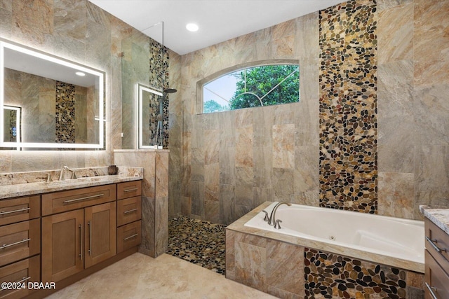 bathroom with tile walls, vanity, and independent shower and bath