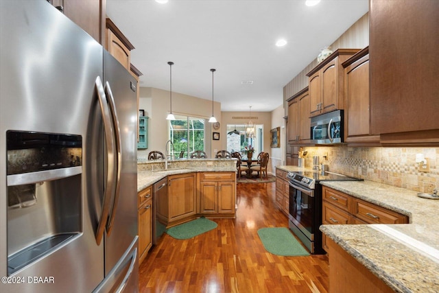 kitchen with dark wood-type flooring, sink, hanging light fixtures, kitchen peninsula, and stainless steel appliances