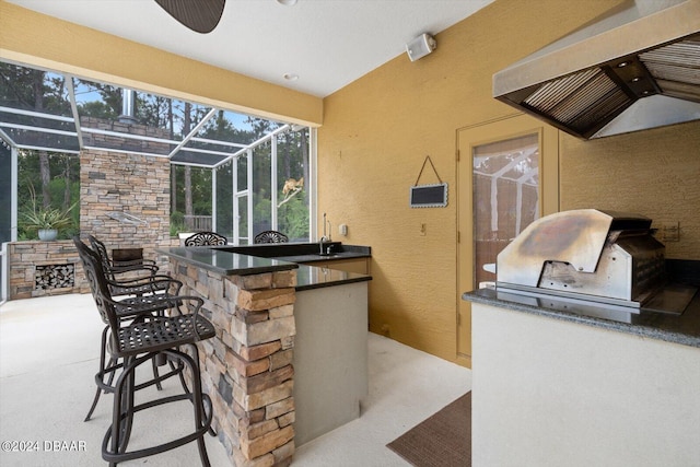 view of patio with a grill, a lanai, exterior kitchen, and exterior bar