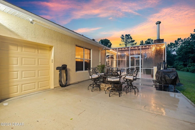 patio terrace at dusk featuring a grill and a sunroom