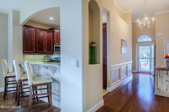 kitchen with pendant lighting, a chandelier, stainless steel appliances, backsplash, and a kitchen breakfast bar