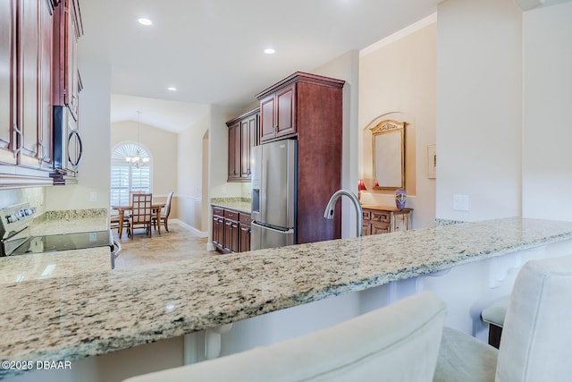 kitchen with a breakfast bar area, stainless steel appliances, kitchen peninsula, an inviting chandelier, and lofted ceiling